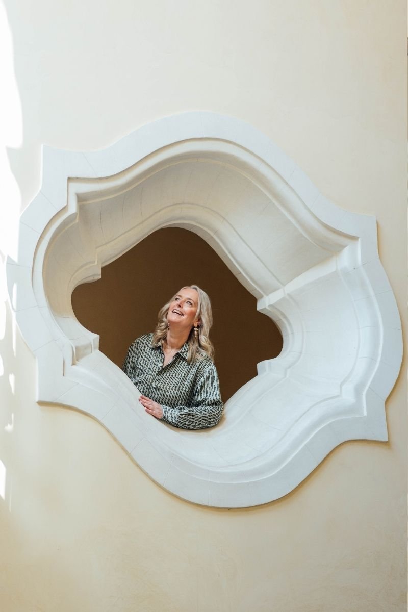 Marina Adrian lacht in einem ornamentalen Fenster
