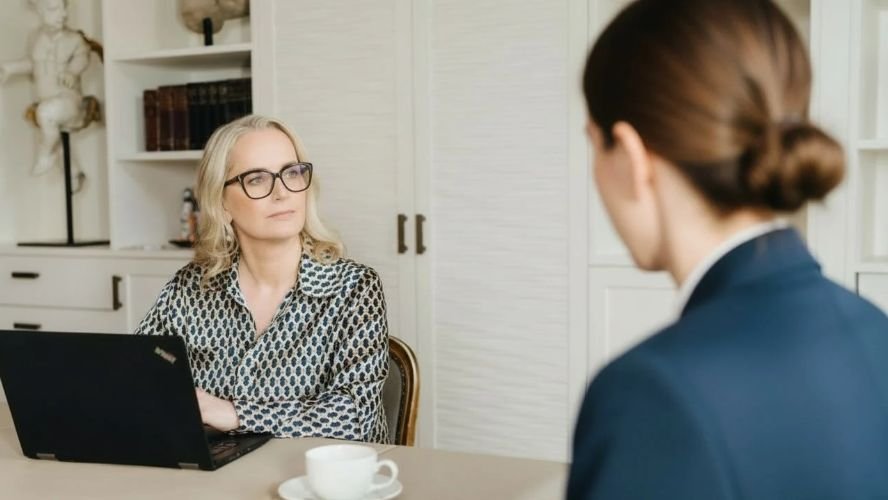 Marina Adrian am Tisch im Gespr&auml;ch, ihr gegen&uuml;ber eine Frau von hinten