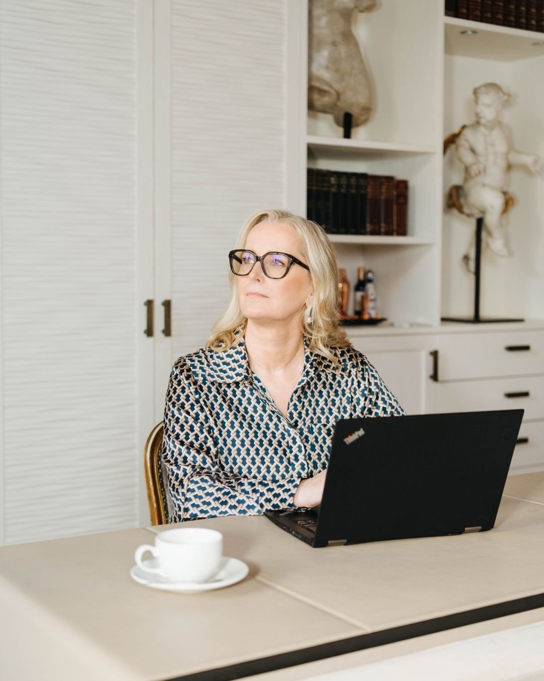 Marina Adrian sitzt am Laptop und schaut nachdenklich zur Seite