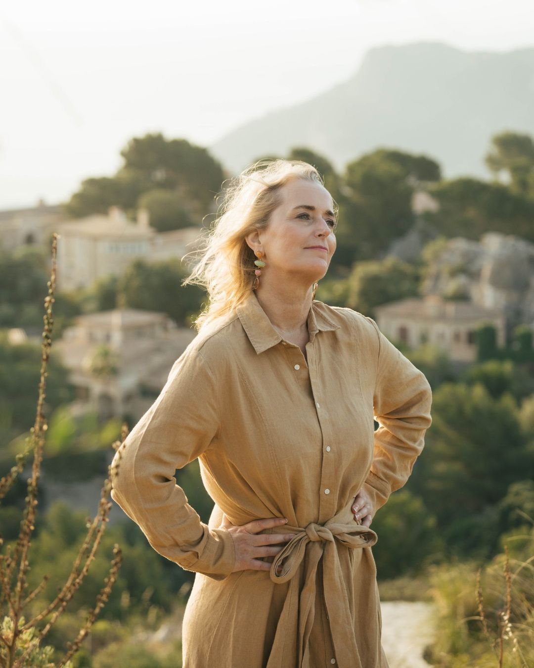 Marina Adrian blickt ruhig in die Weite, hinter ihr H&uuml;gel und H&auml;user im Abendlicht