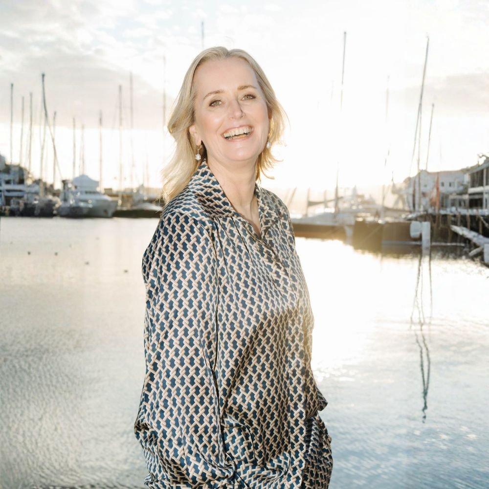 Marina Adrian lacht offen in die Kamera, hinter ihr ein Hafen im Gegenlicht